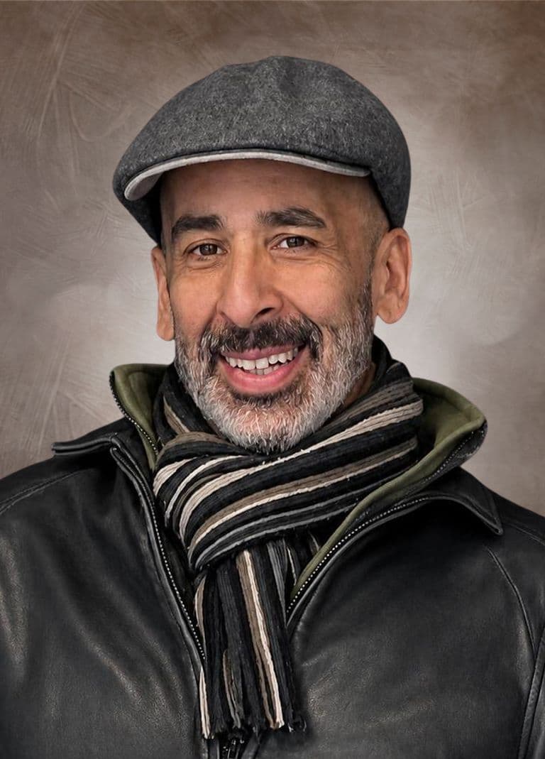 Brian smiling, wearing a grey cap and striped scarf